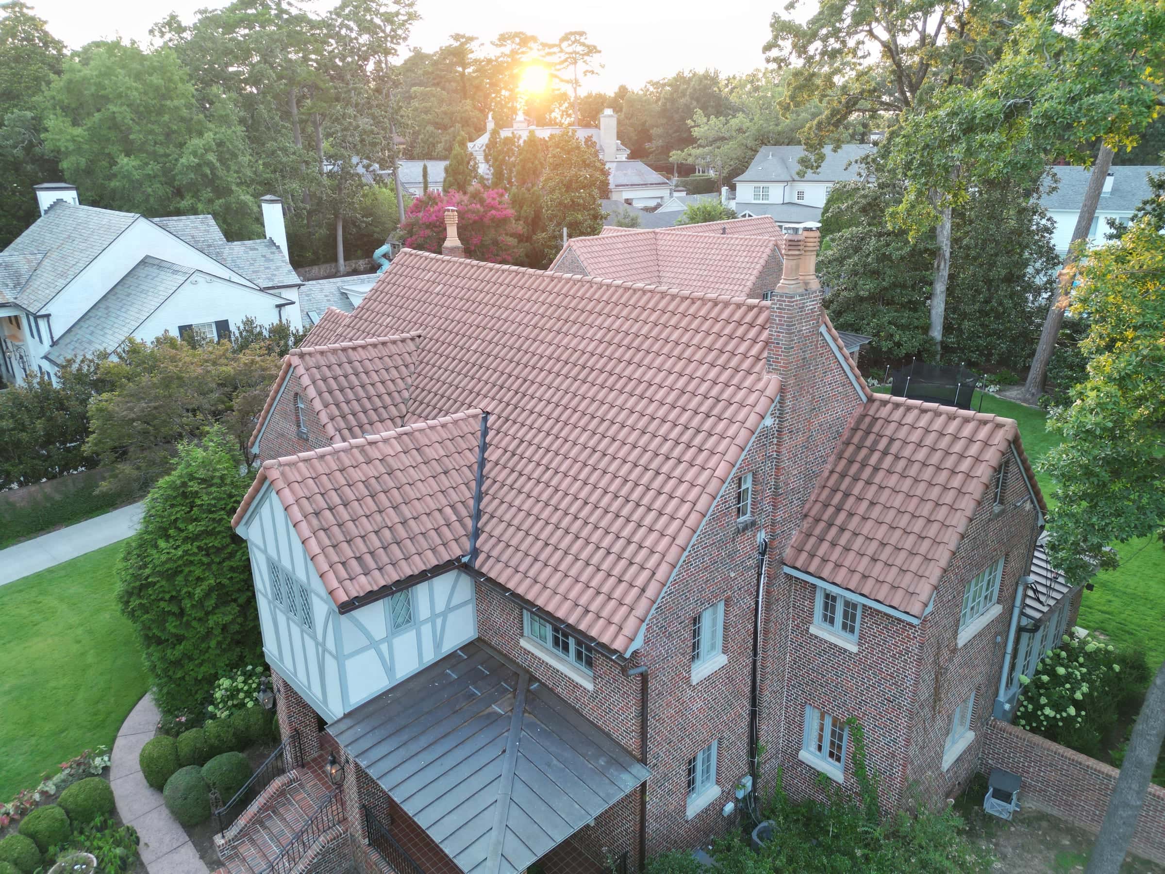 Brick Tudor home with a red clay tile roof seen from above