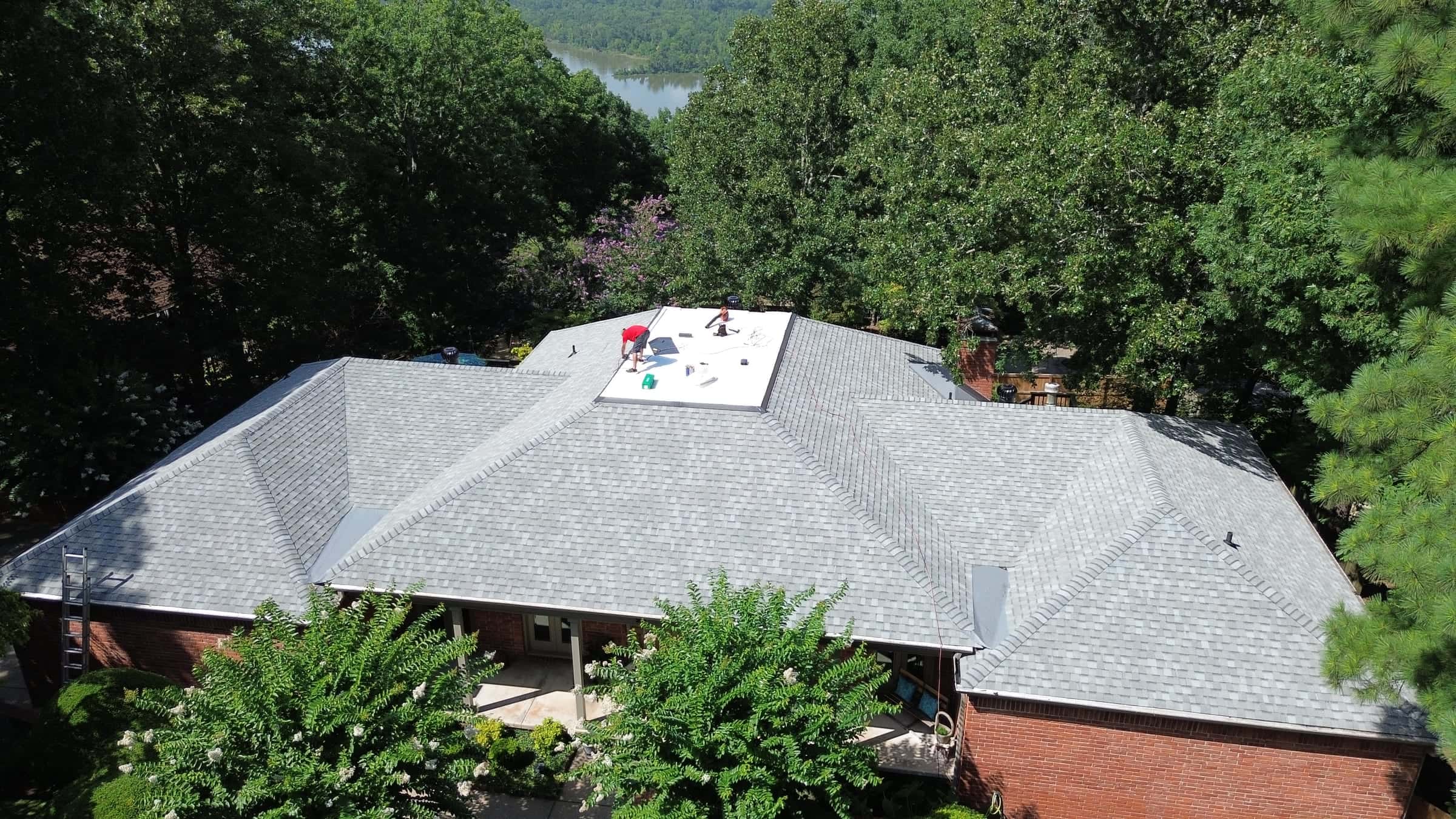 Roofing crew working on a shingle roof replacement on a brick home