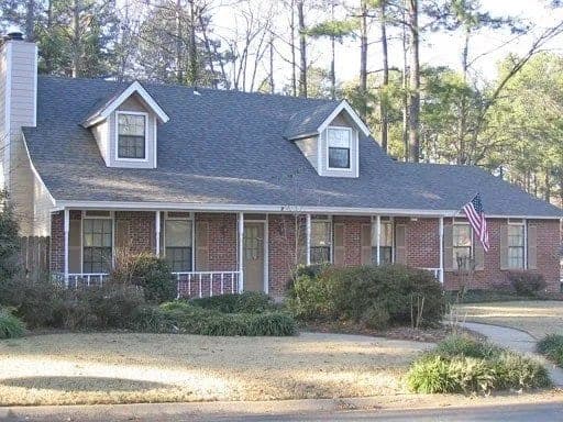 Cape Cod style brick home with dormers and an asphalt shingle roof