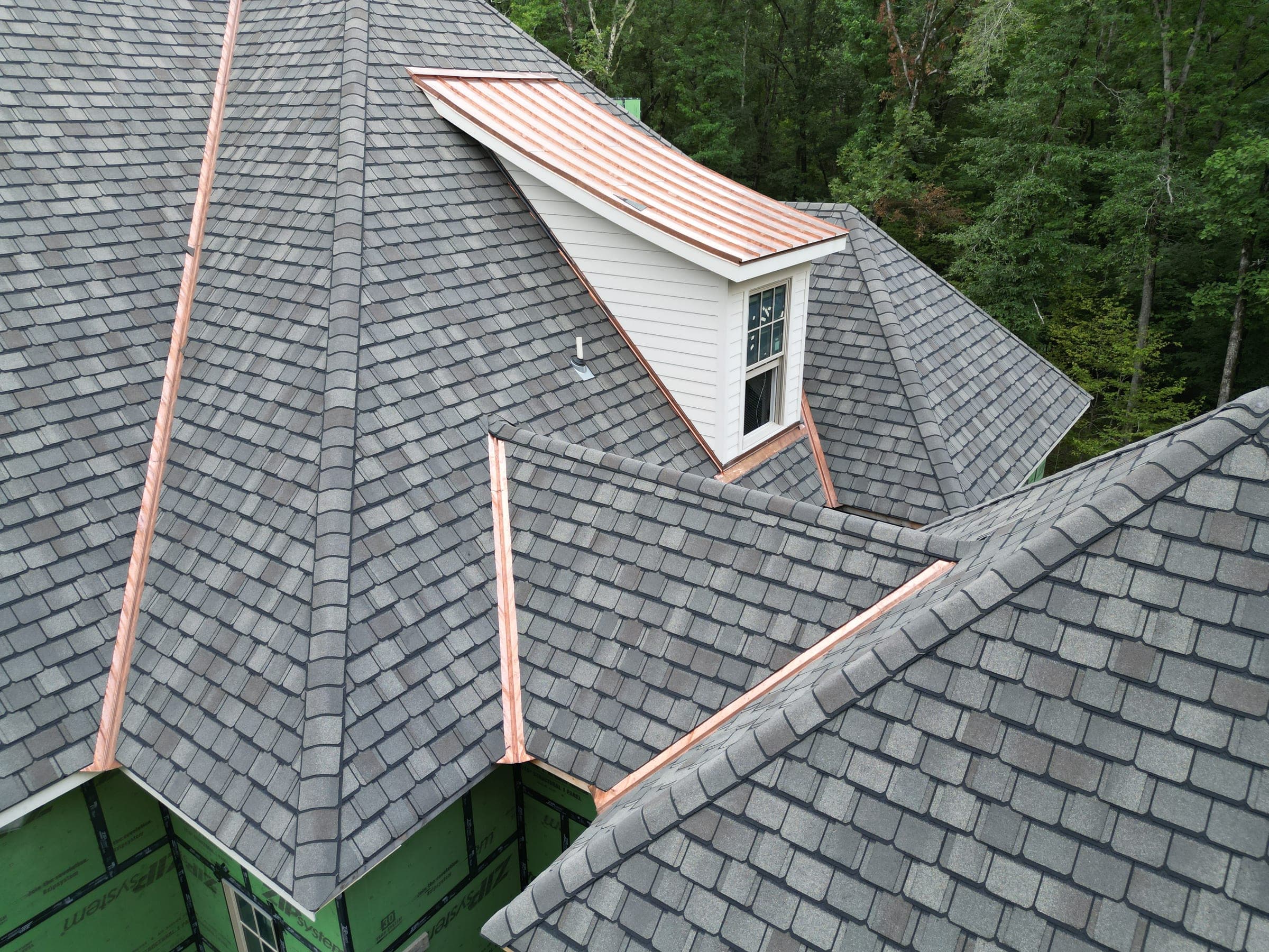 Close aerial view of a hand-fitted copper valley running beside a dormer on a slate-look roof