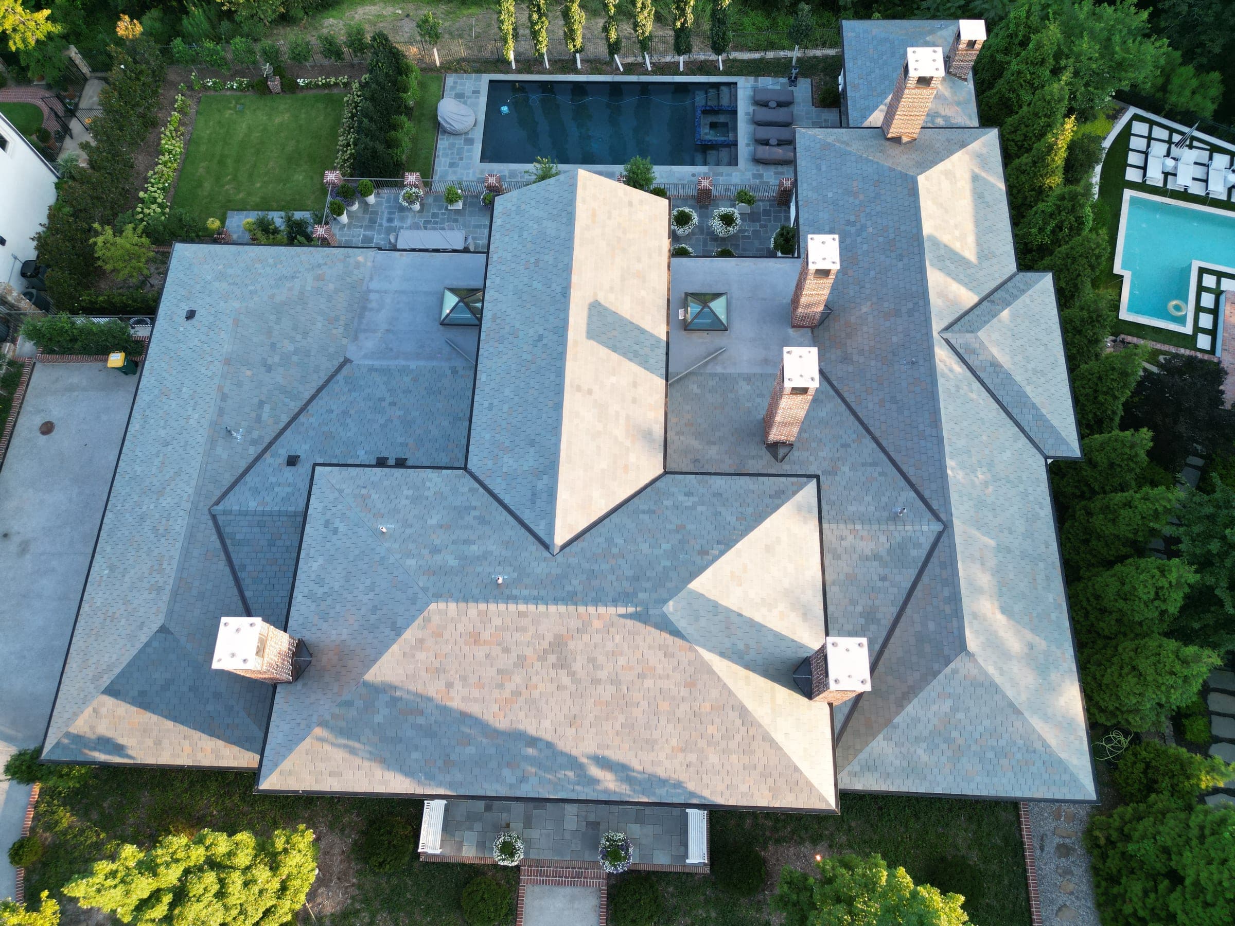 Top-down aerial of an estate roof with multiple chimneys and a skylight