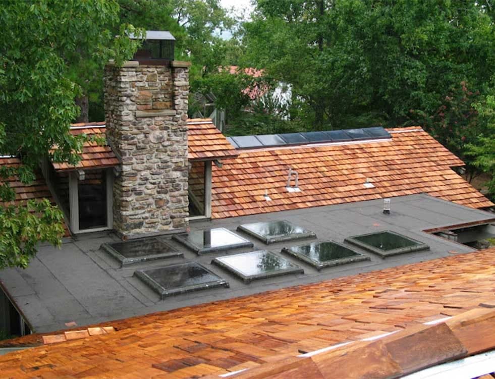 Cedar wood shake roof with a stone chimney and skylights