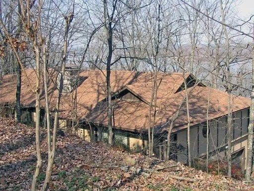 Wooded hillside home with a weathered cedar shake roof