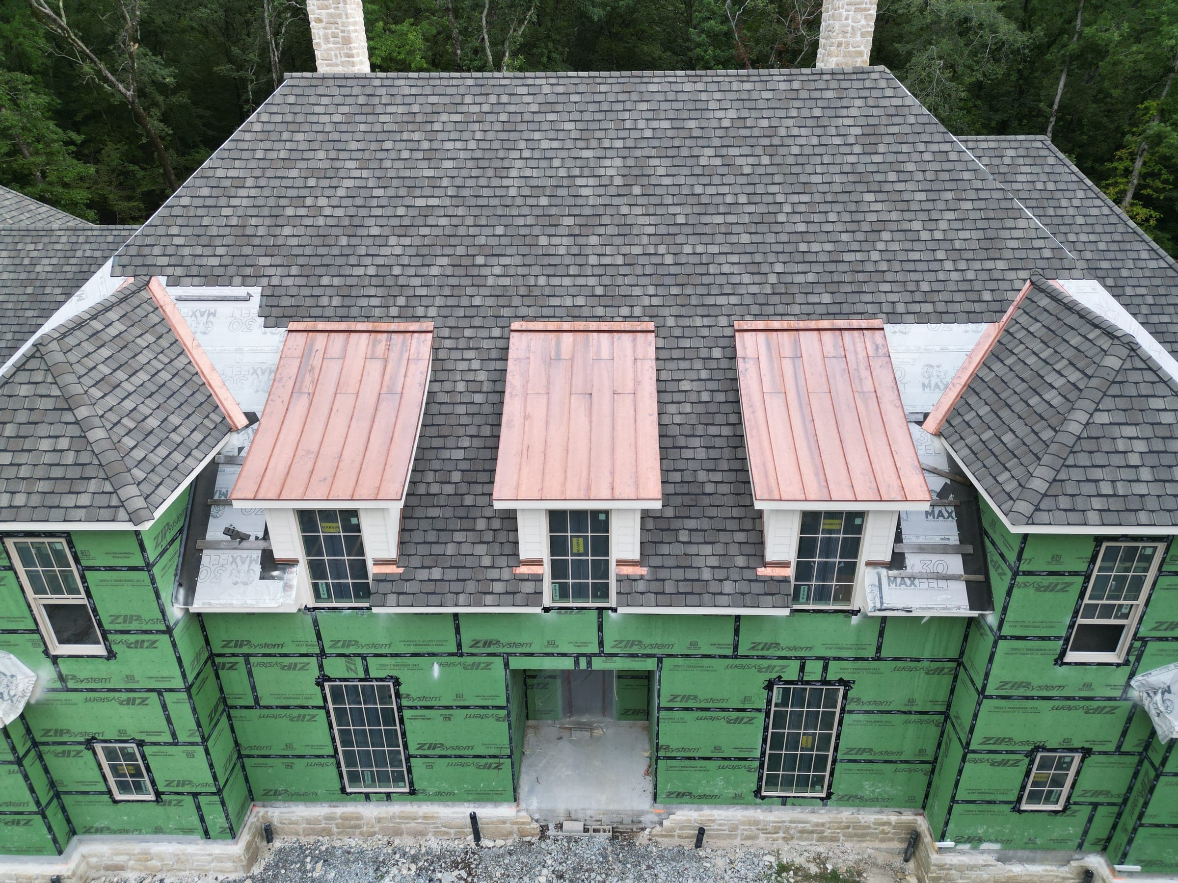Three copper-roofed dormers on a new-construction home